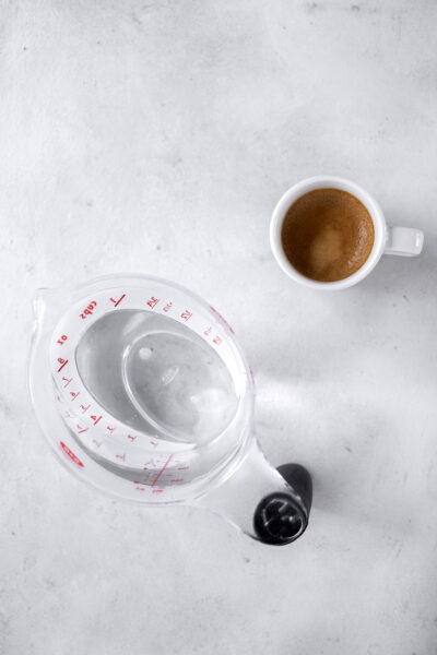 Espresso and measuring cup of water.