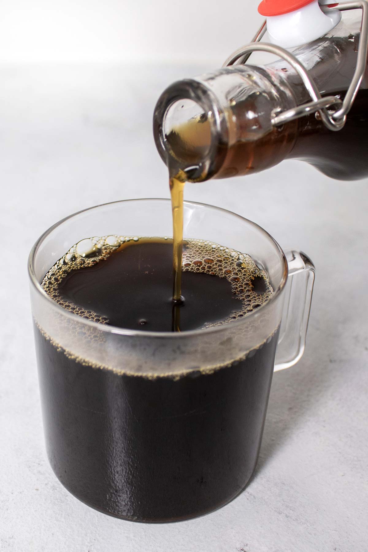 Pouring brown sugar syrup into a cup of coffee.