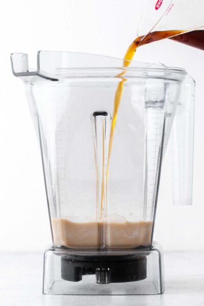 Coffee poured into a blender with oat milk. 