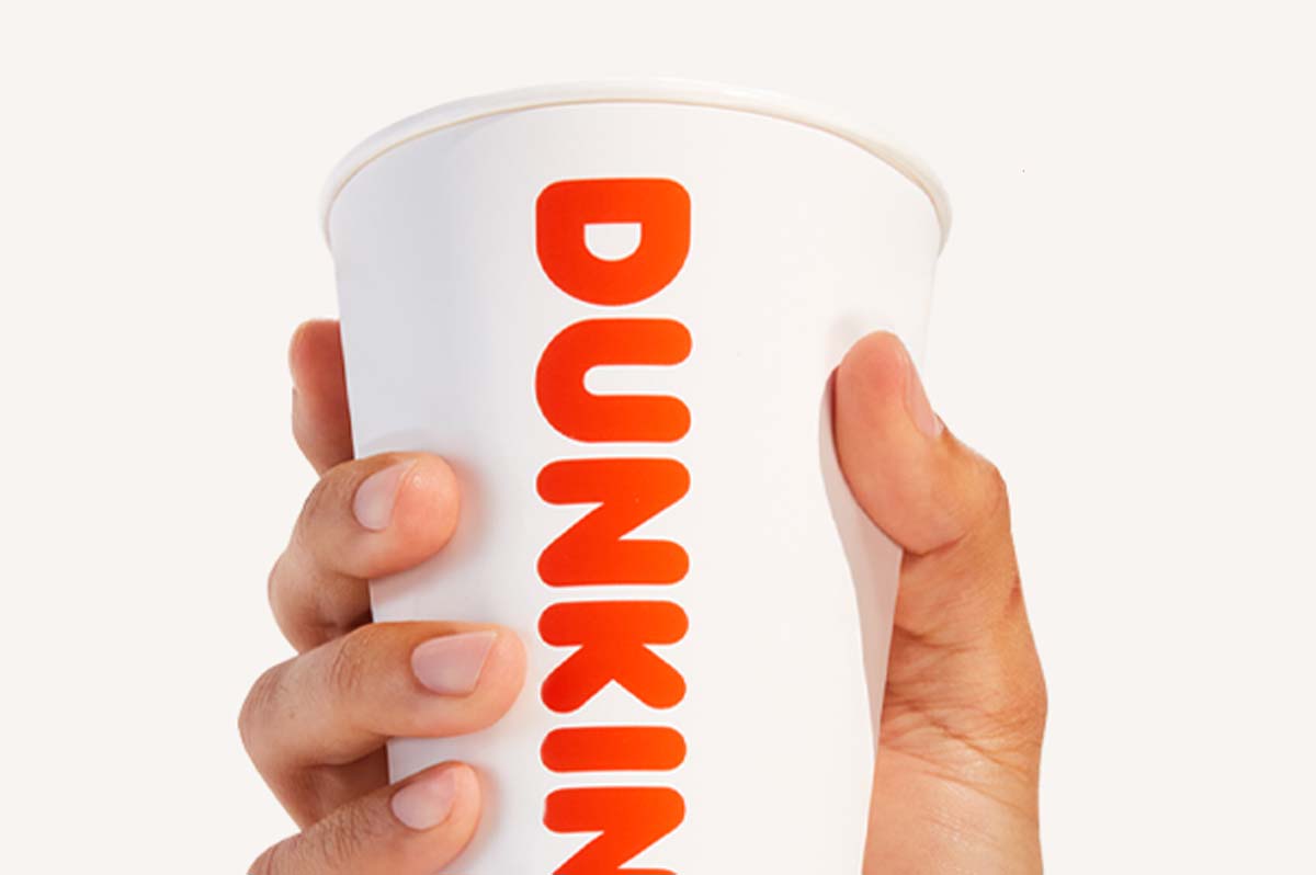 Hand holding Dunkin' cup.