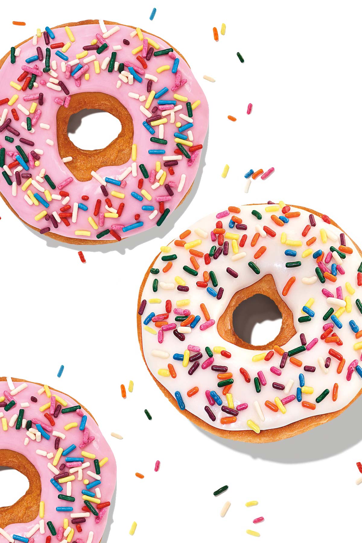 Two strawberry-frosted sprinkled donuts and one vanilla-frosted sprinkled donuts from Dunkin' on a white background.