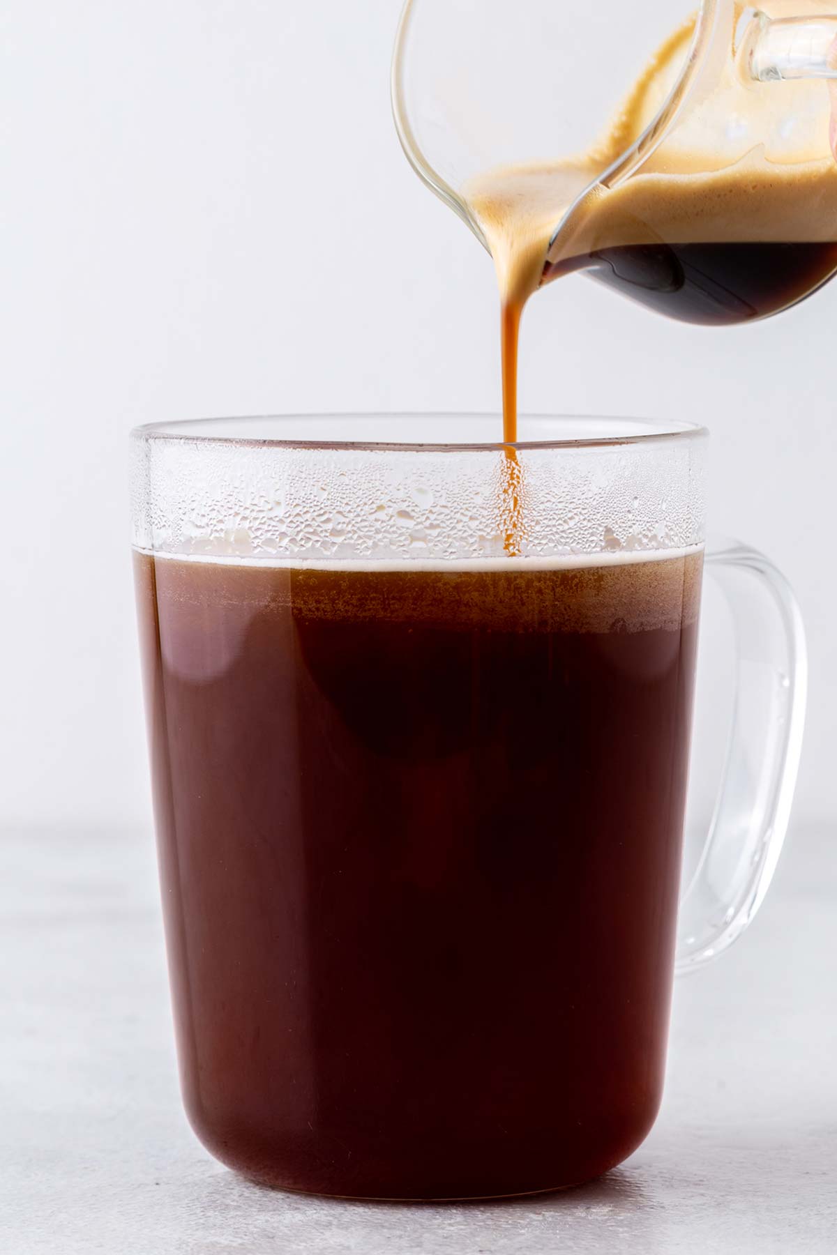 Pouring espresso into a mug with hot water.