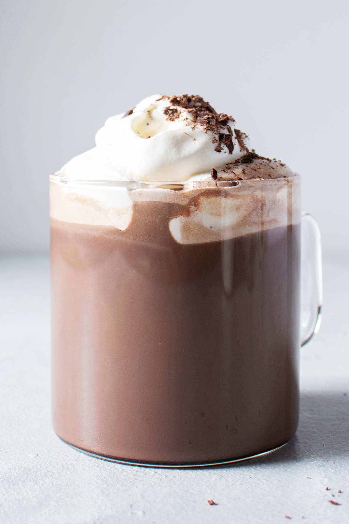 Hot chocolate in a glass mug with whipped cream and grated chocolate.