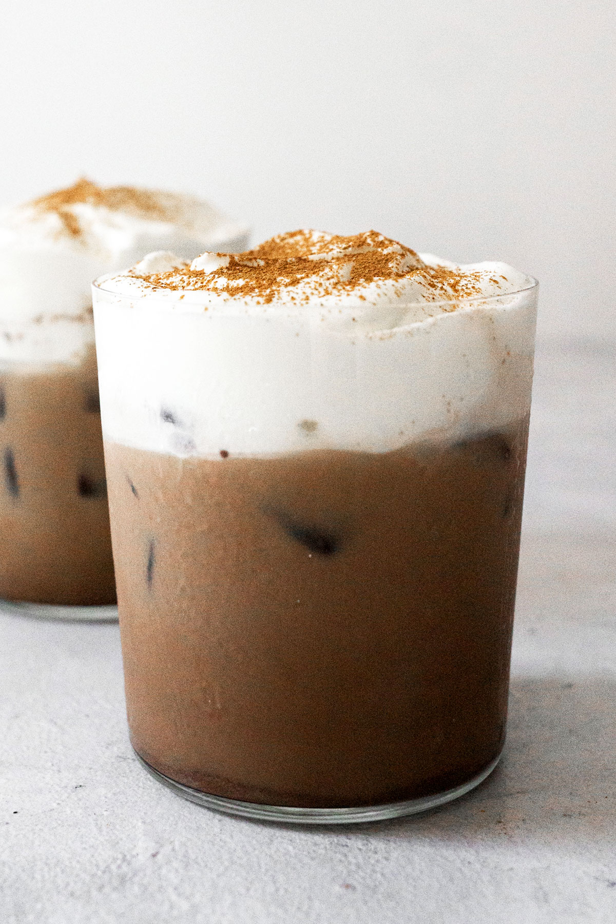 Two cups of iced Mexican coffee with cream topping.