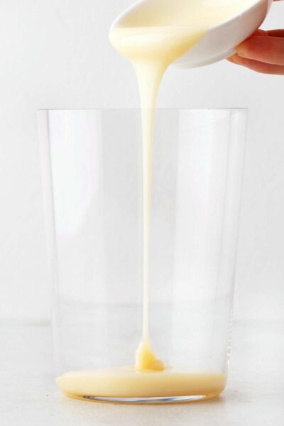 Pouring sweetened condensed milk into a cup.