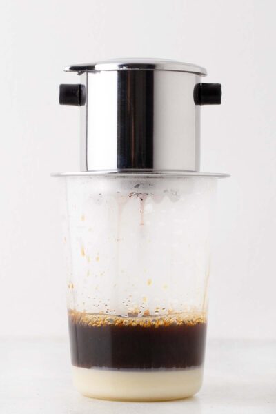 A phin filter on top of a cup making Vietnamese coffee.