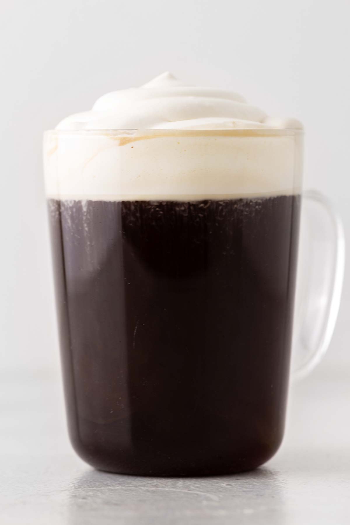 Irish Coffee with cream on top in a glass cup.