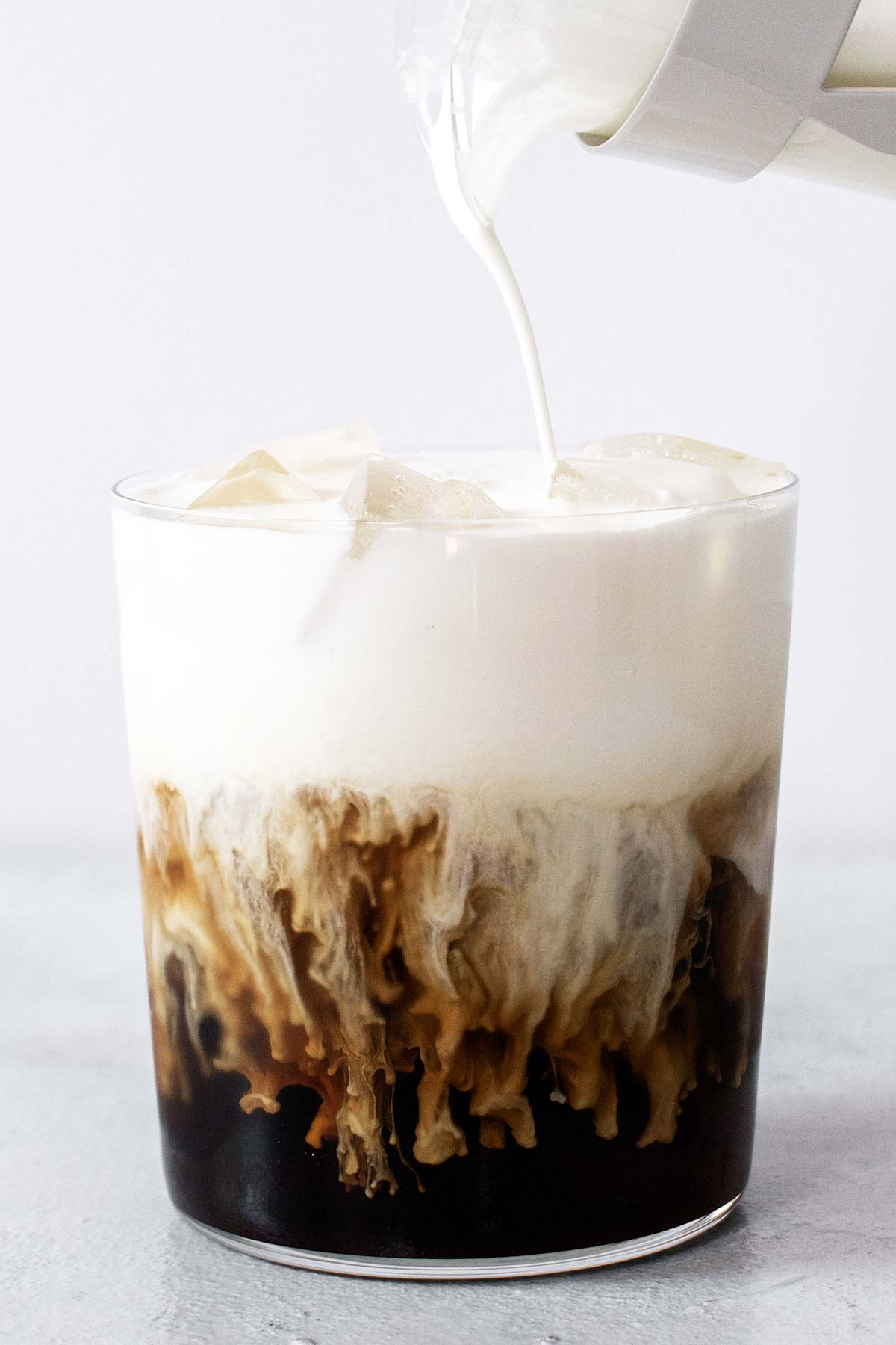 Pouring cold foam onto an Irish Cream Cold Brew with Cold Foam drink.
