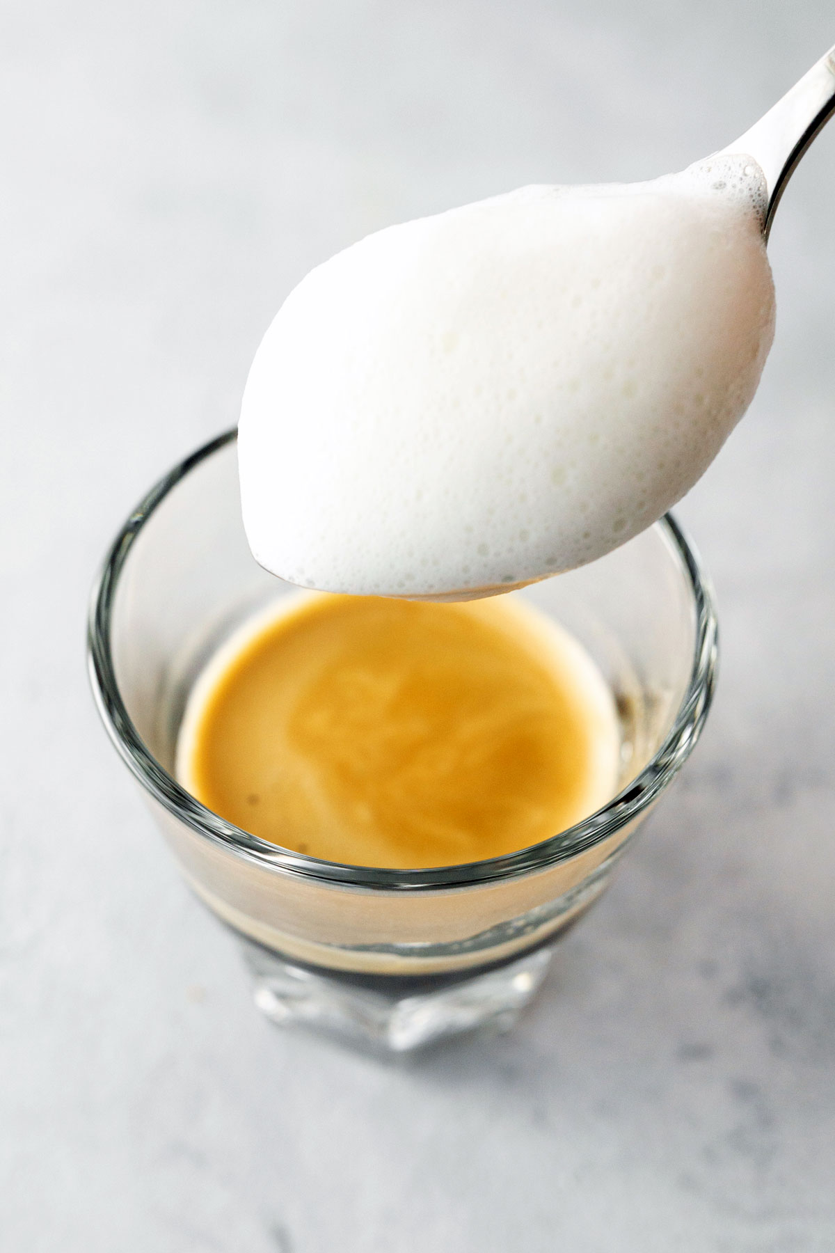 Spooning milk foam onto a cup of espresso.