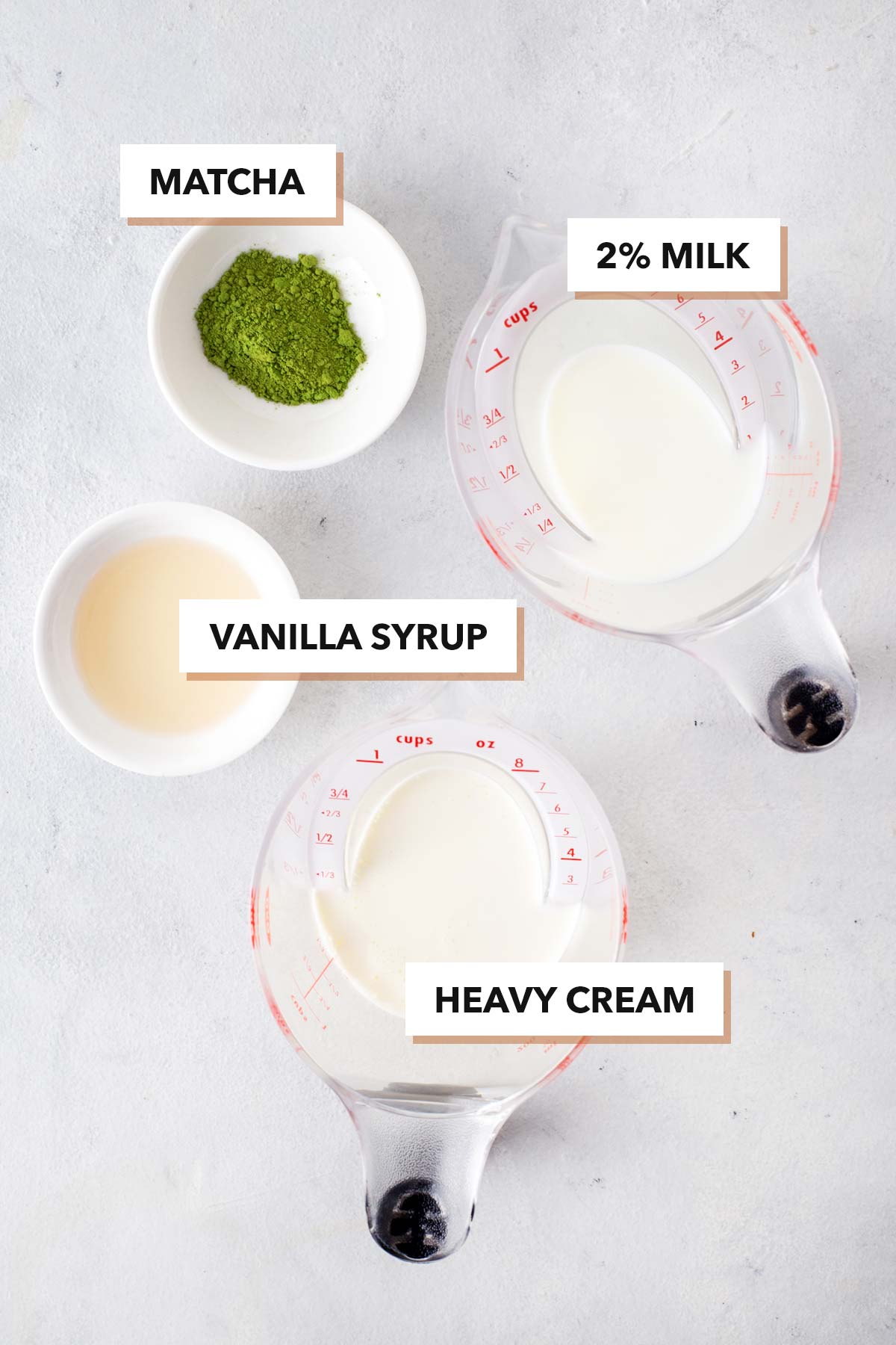 Ingredients for matcha cold foam in measuring cups on a table.