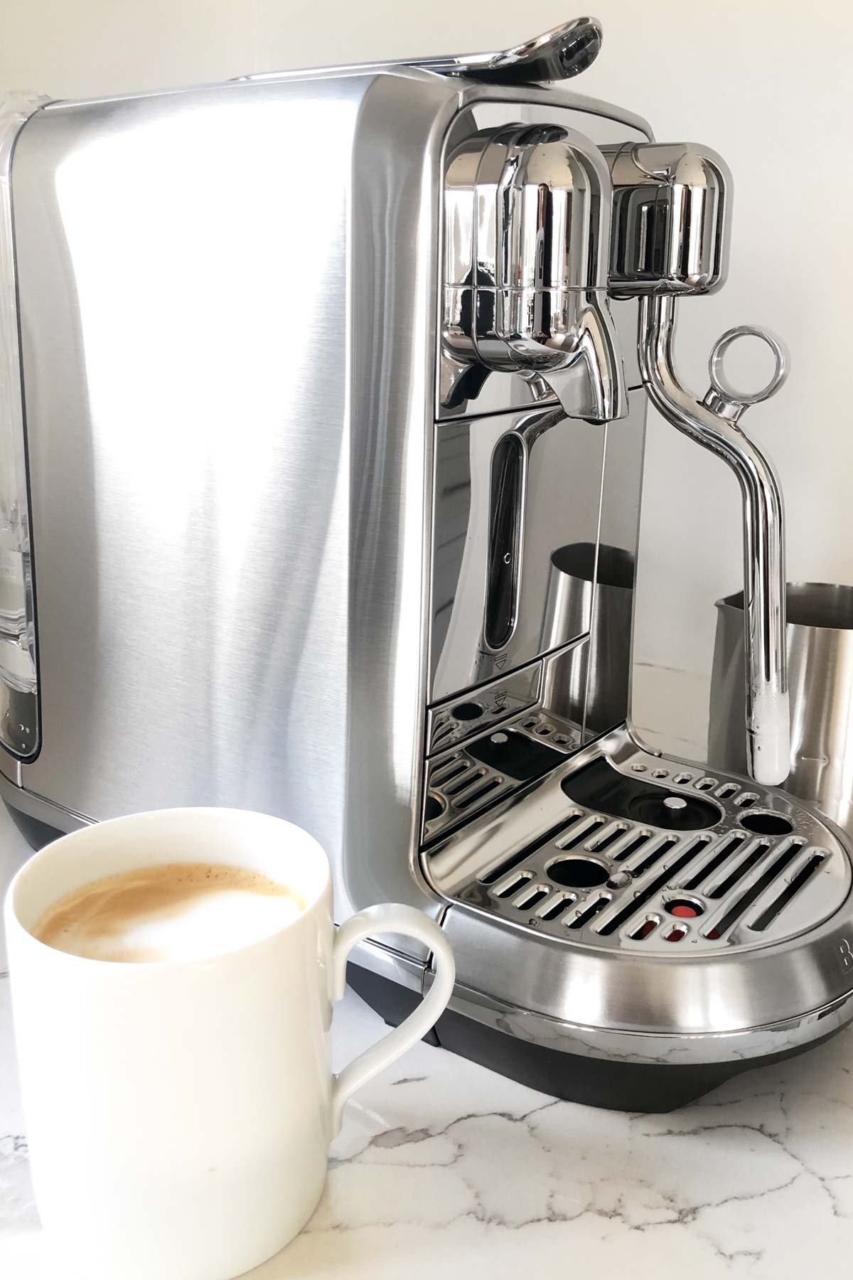 Nespresso Creatista Plus machine with finished hot latte in a mug.