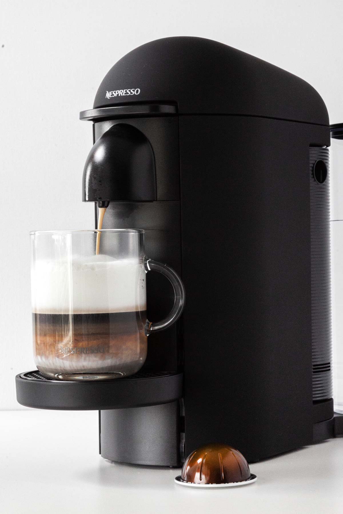 Making a drink with espresso and milk using a Nespresso machine.