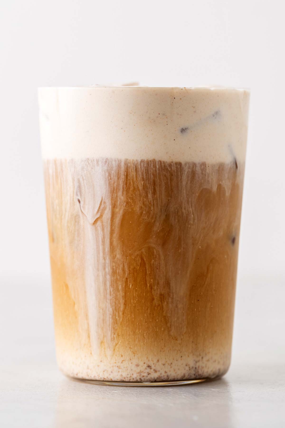 Pumpkin Cream Cold Foam on top of iced coffee in a cup.