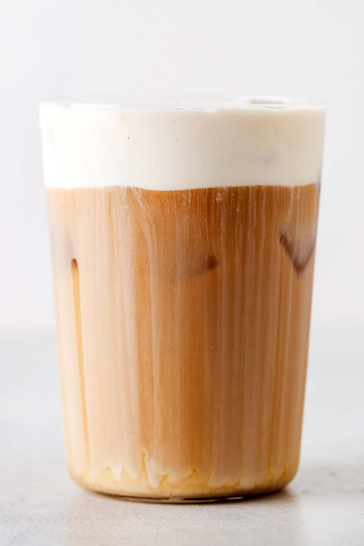 Busa dingin karamel asin di atas es kopi.