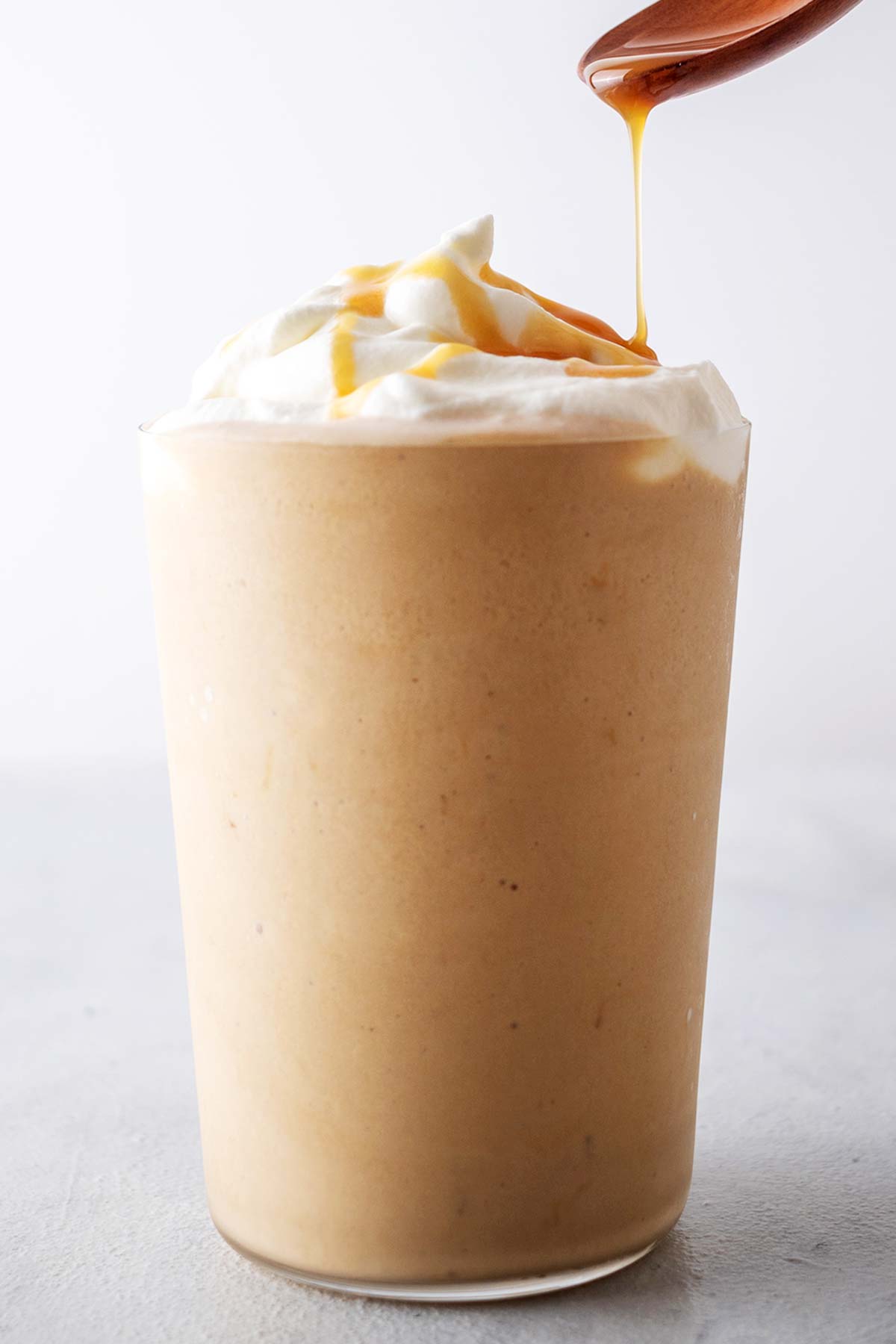Drizzling caramel sauce on a Caramel Frappuccino with whipped cream.