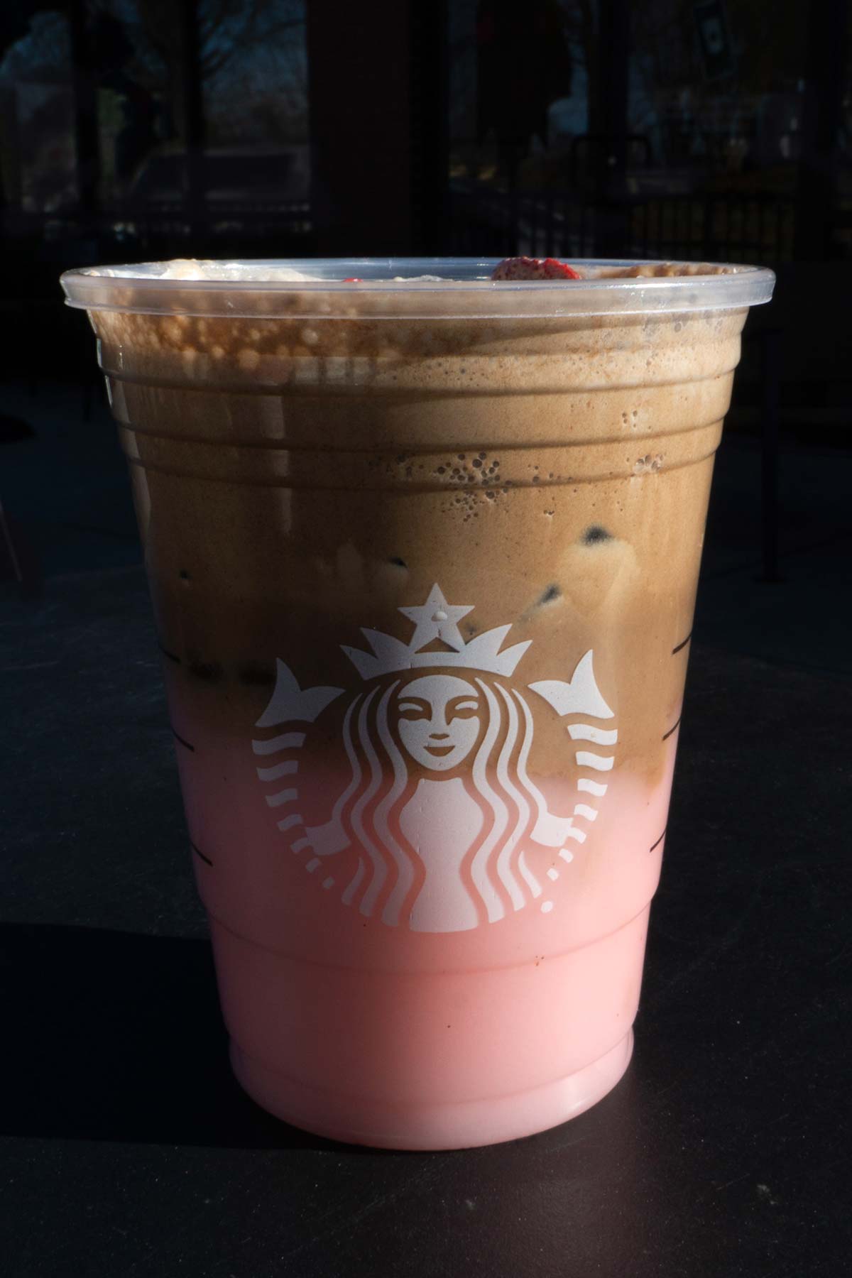 Large cup of Starbucks layered Pink Drink with chocolate cold foam and dried strawberries in a cup.