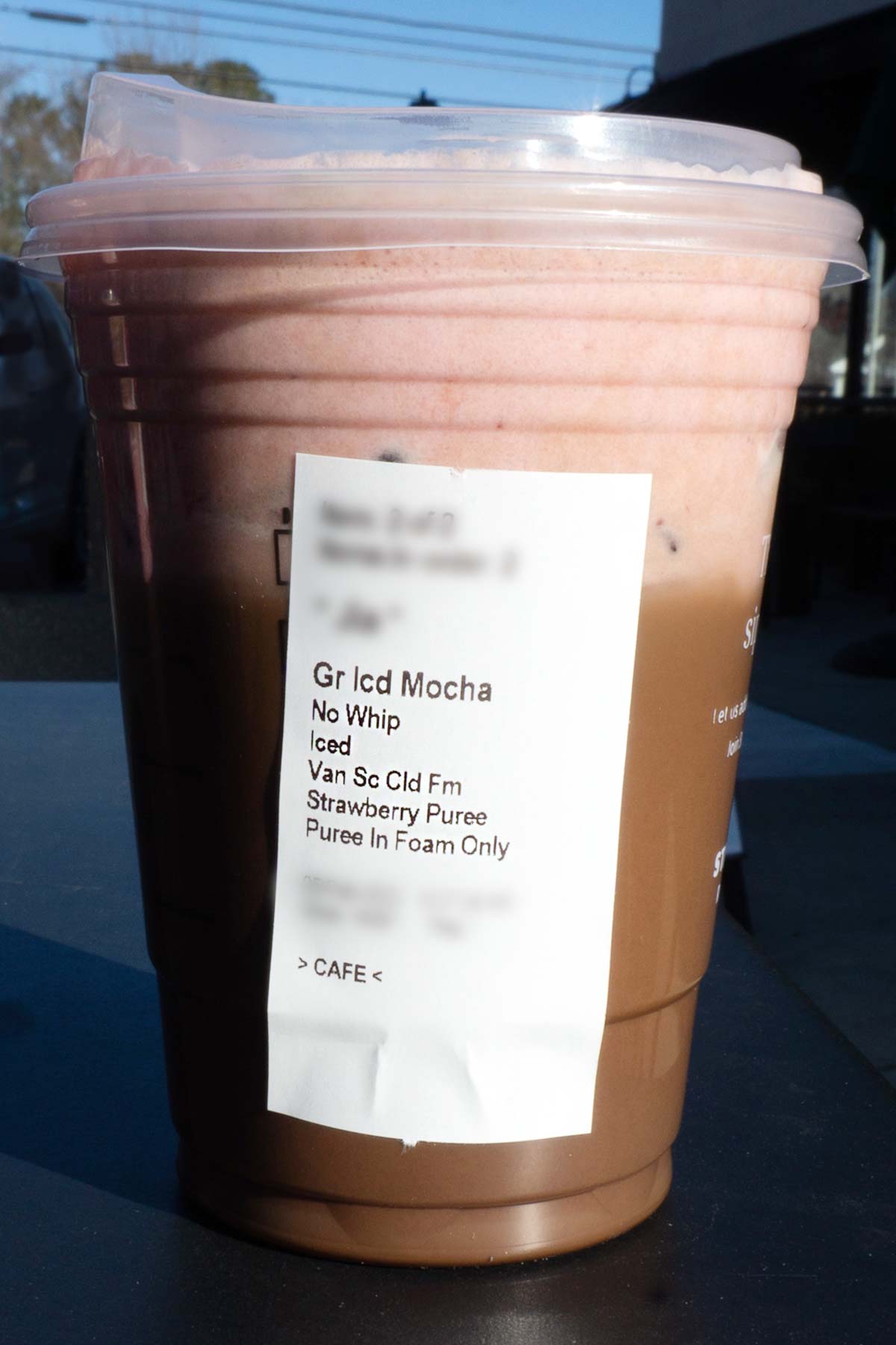 Grande sized Starbucks layered mocha and strawberry drink in a cup with the ingredients listed on a label on the cup.