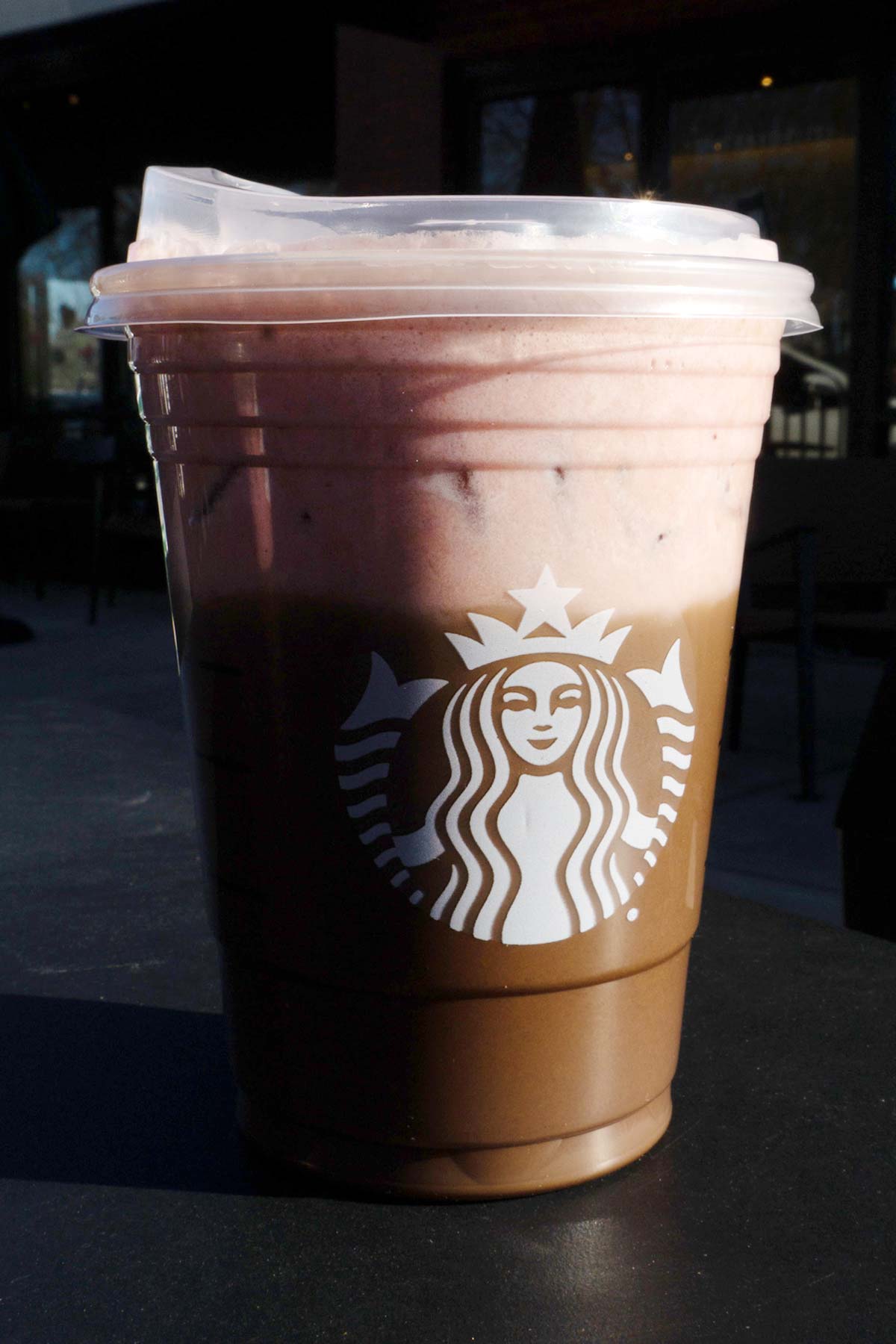 Starbucks layered mocha and strawberry drink in a cup with a lid.