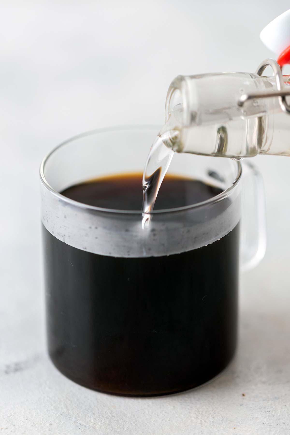 A bottle of classic syrup being poured into a cup of coffee.