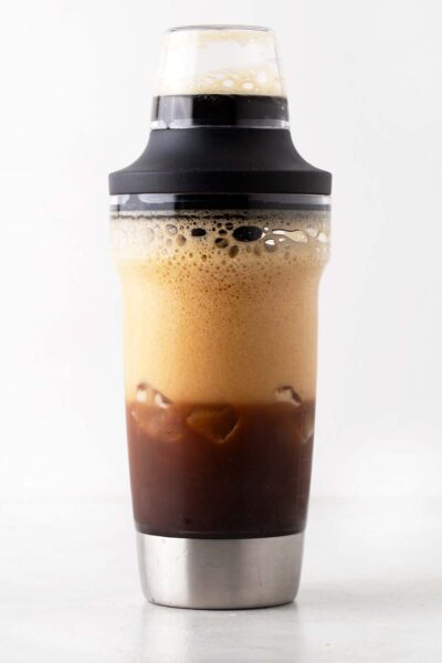 Simple syrup, espresso, and ice in a cocktail shaker. 