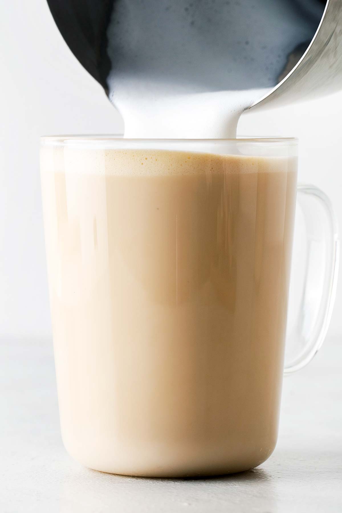 Menuangkan susu berbusa ke dalam latte.