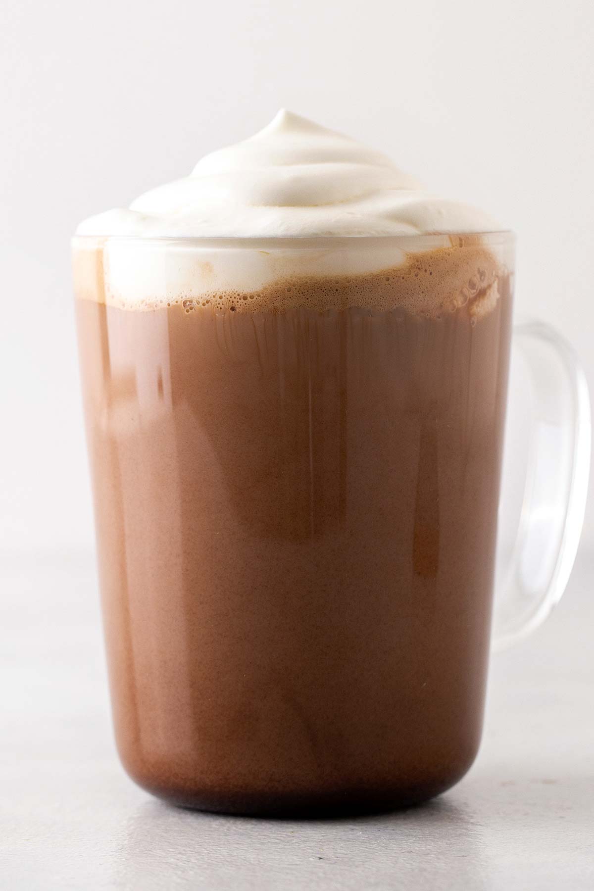 Kopi latte resep Starbucks Mocha dalam cangkir bening, atasnya dengan krim kocok.