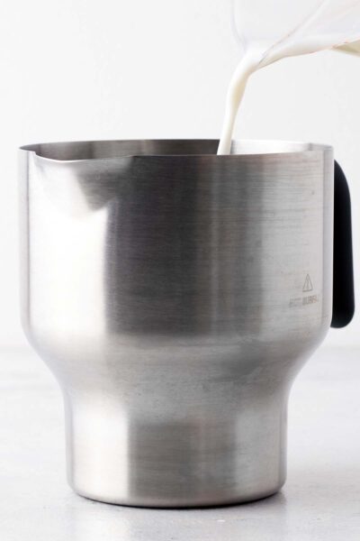Pouring milk into a electric frother. 