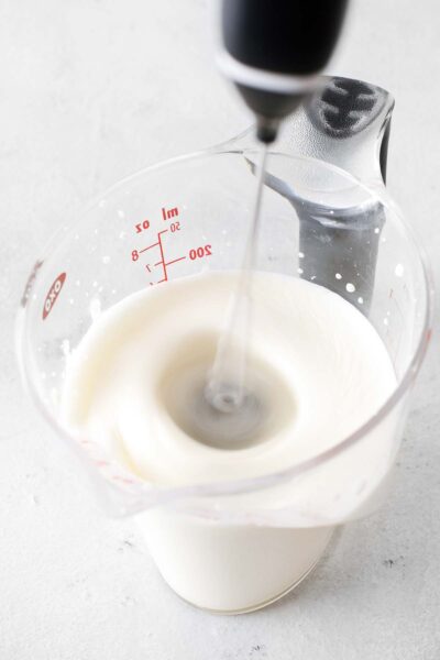 Frothing milk in a measuring cup. 