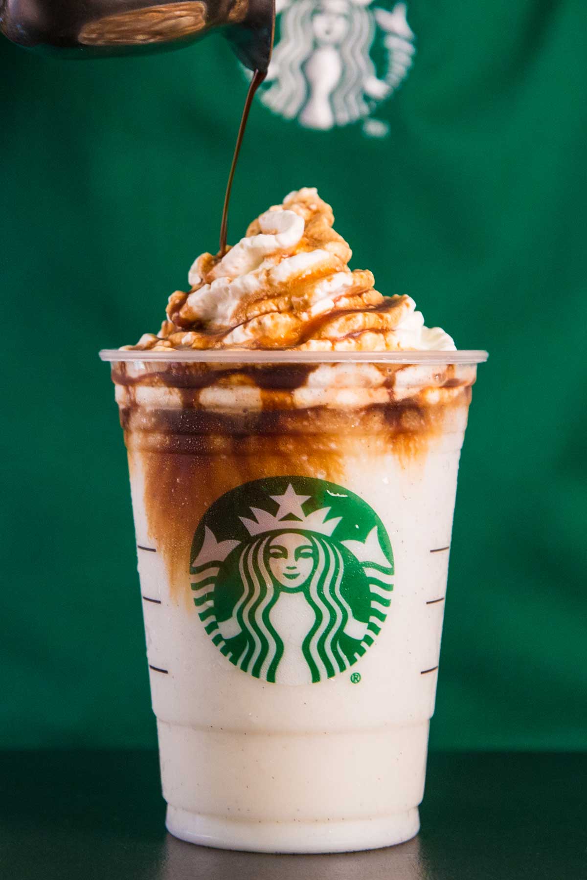 Pouring chocolate sauce on top of a Starbucks drink with whipped cream.