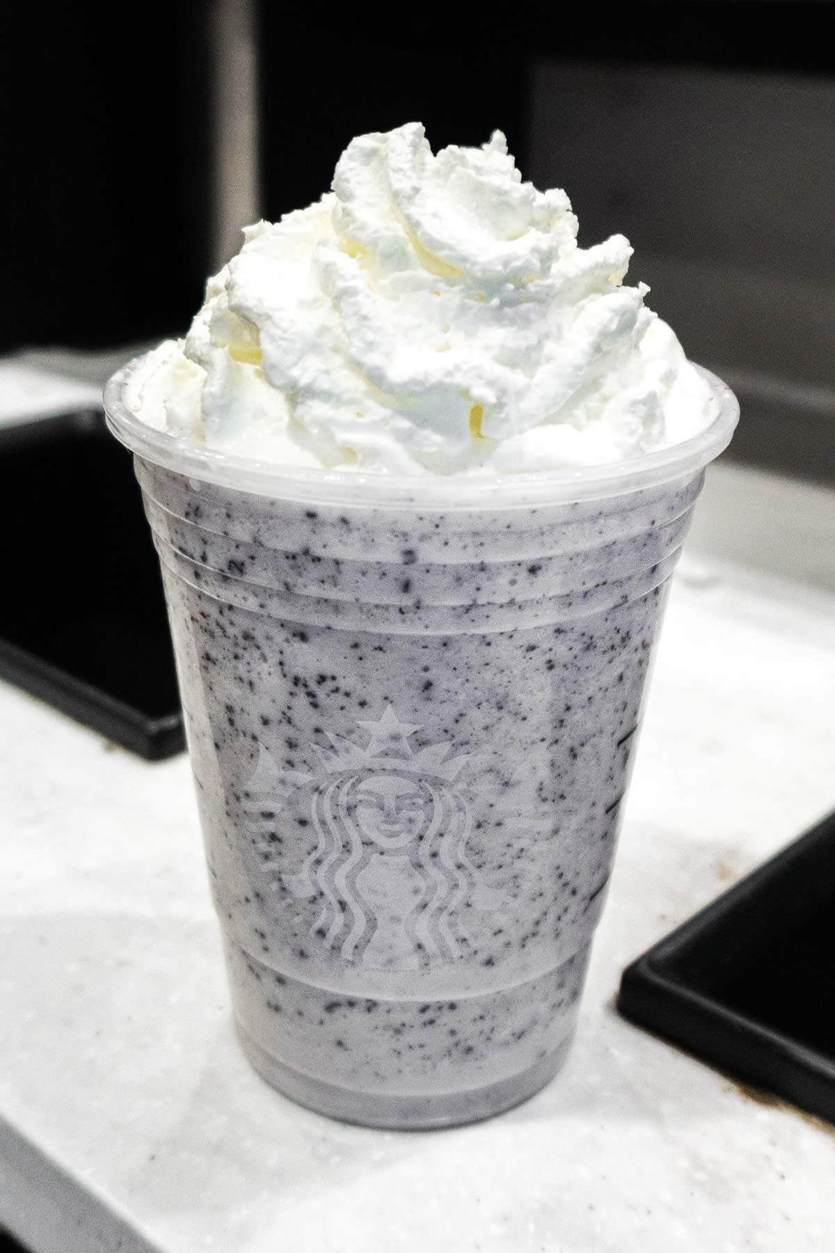 Cookies and Cream Frappuccino in a Starbucks cup with the lid off and whipped cream on top.