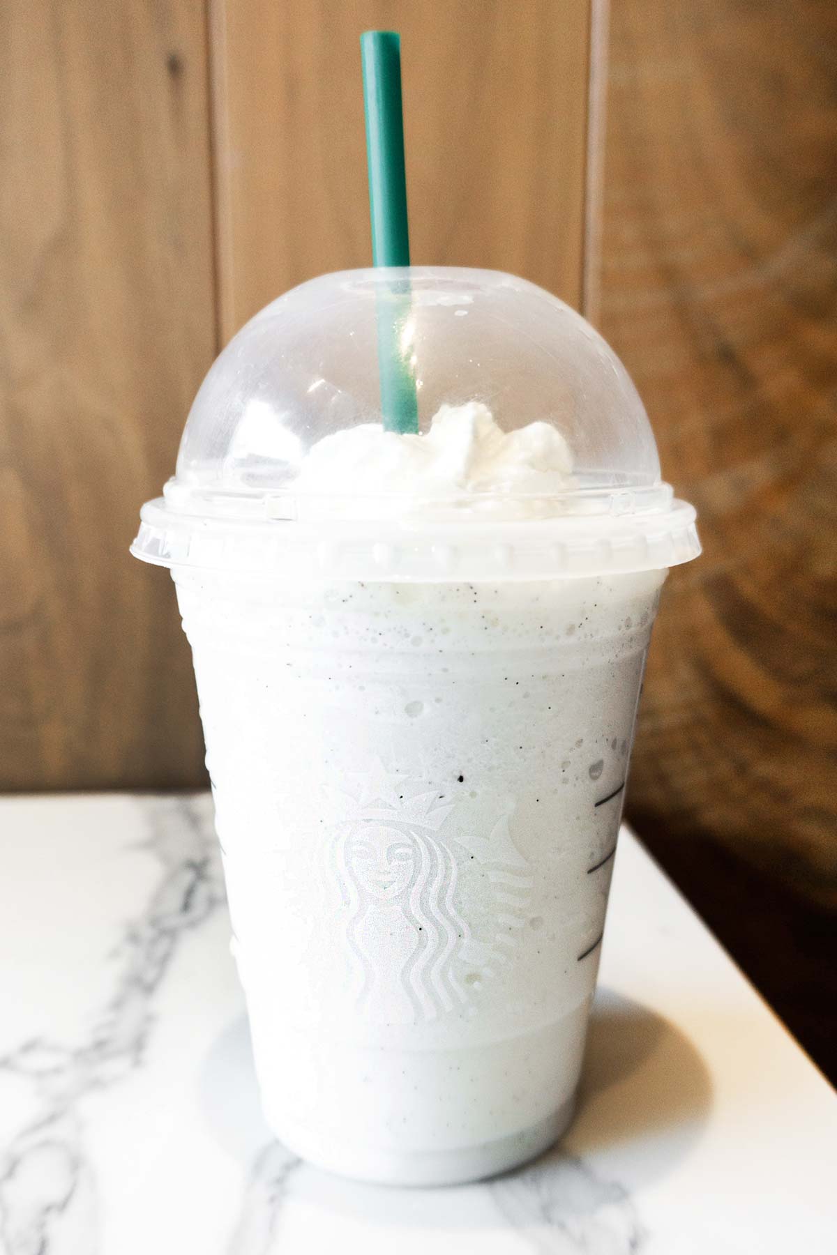 Starbucks Cotton Candy Frappuccino in a cup with whipped cream and a green straw.