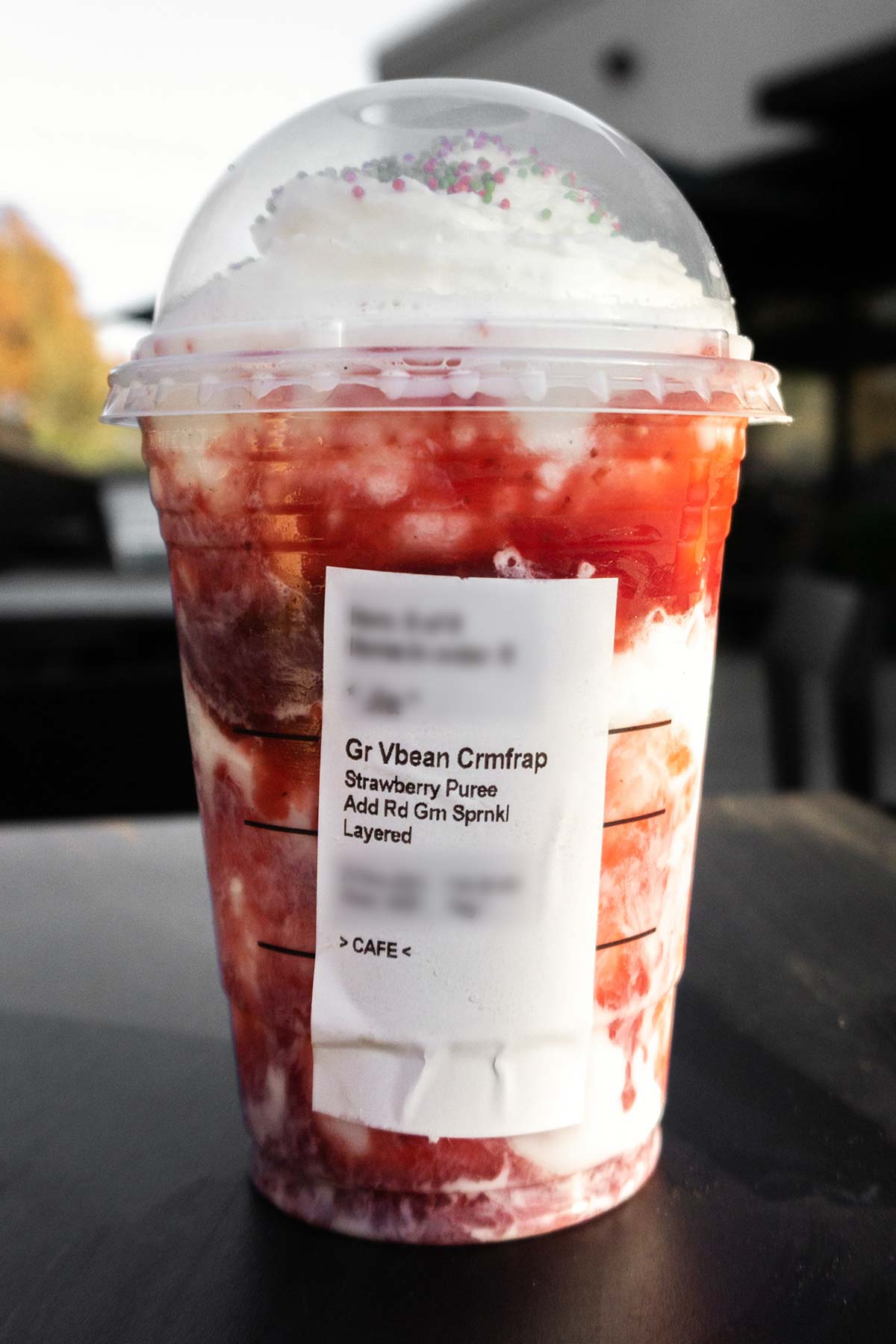 Vanilla frappuccino with strawberry puree layered in and ordering label on the cup.