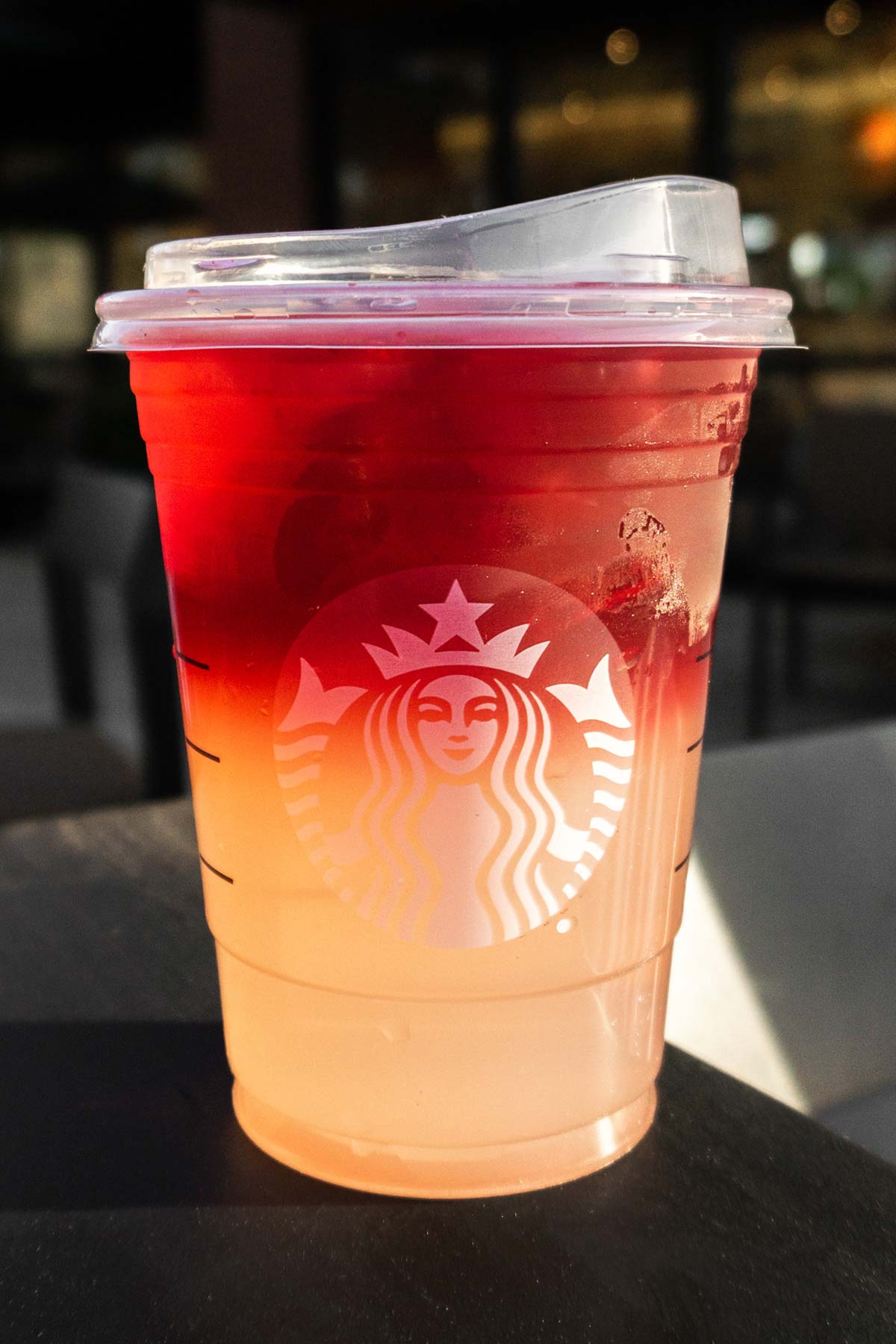 Grande sized Starbucks ombre drink in a cup with a lid.
