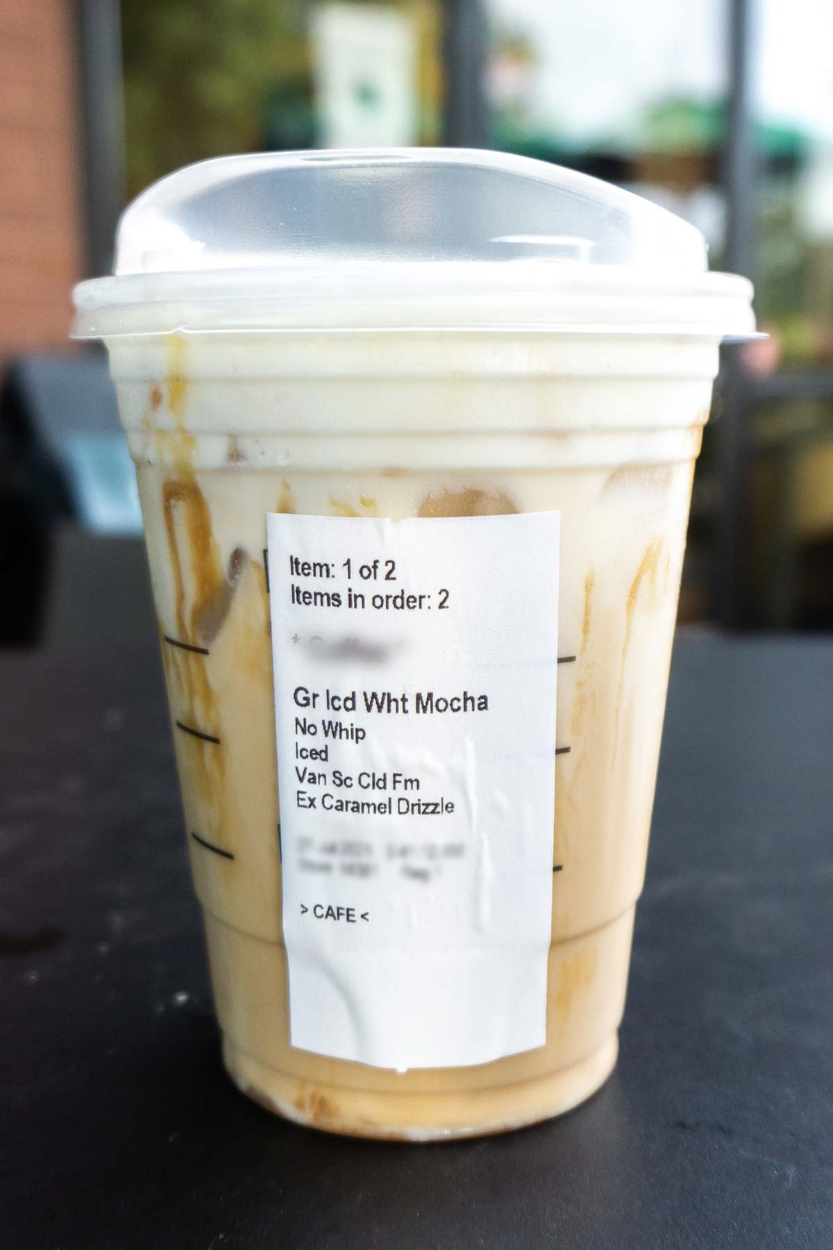 Starbucks drink Iced White Mocha with Sweet Cream Foam and extra caramel drizzle in a plastic cup.