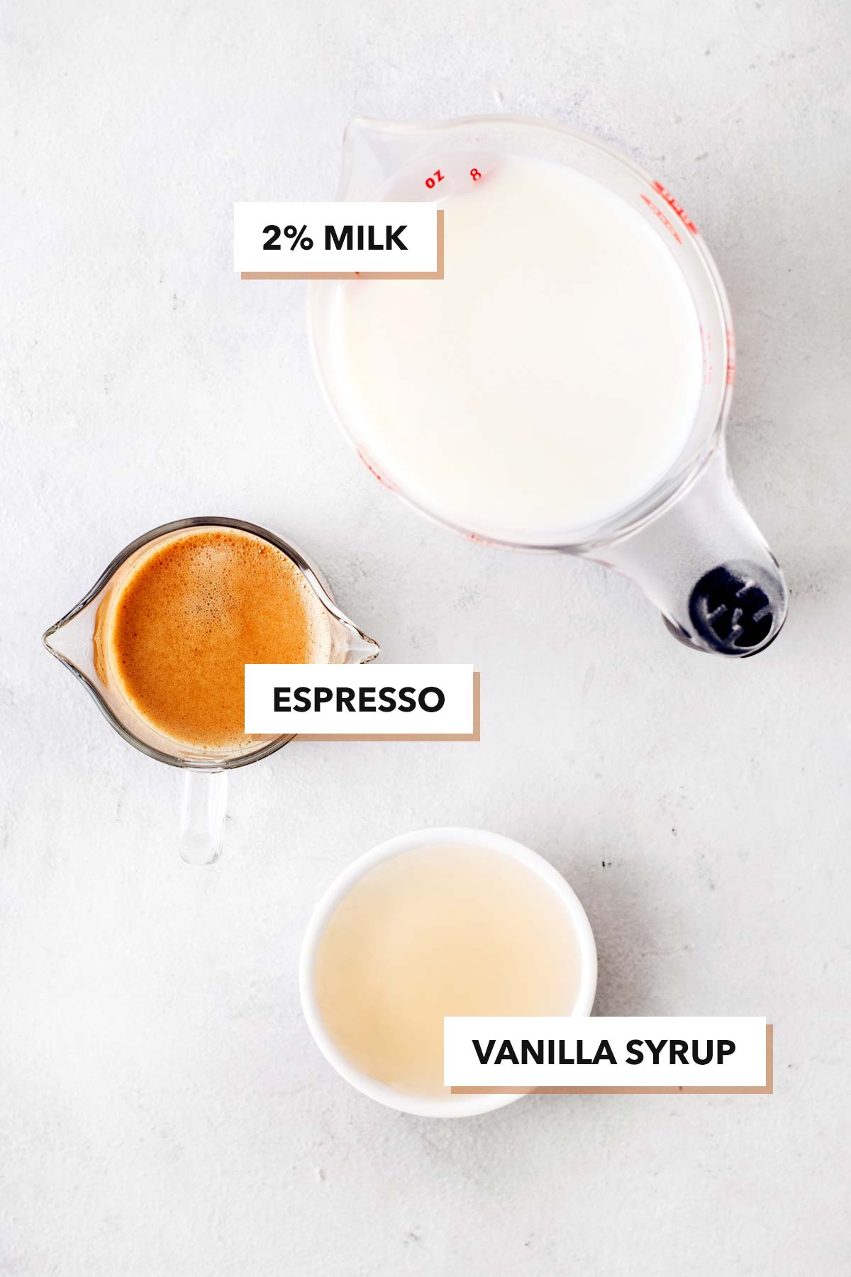 Starbucks Vanilla Latte copycat recipe ingredients in measuring cups on a table.