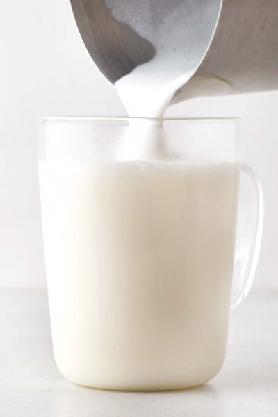 Pouring frothed milk into a glass mug.