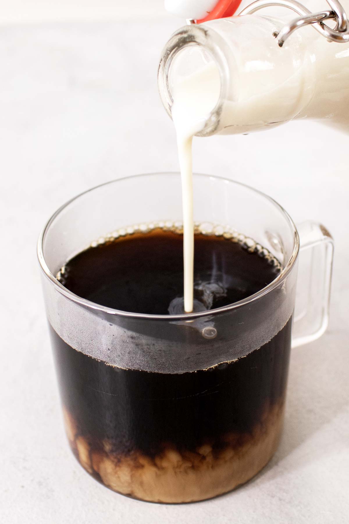 Pouring French vanilla creamer into a cup of coffee.