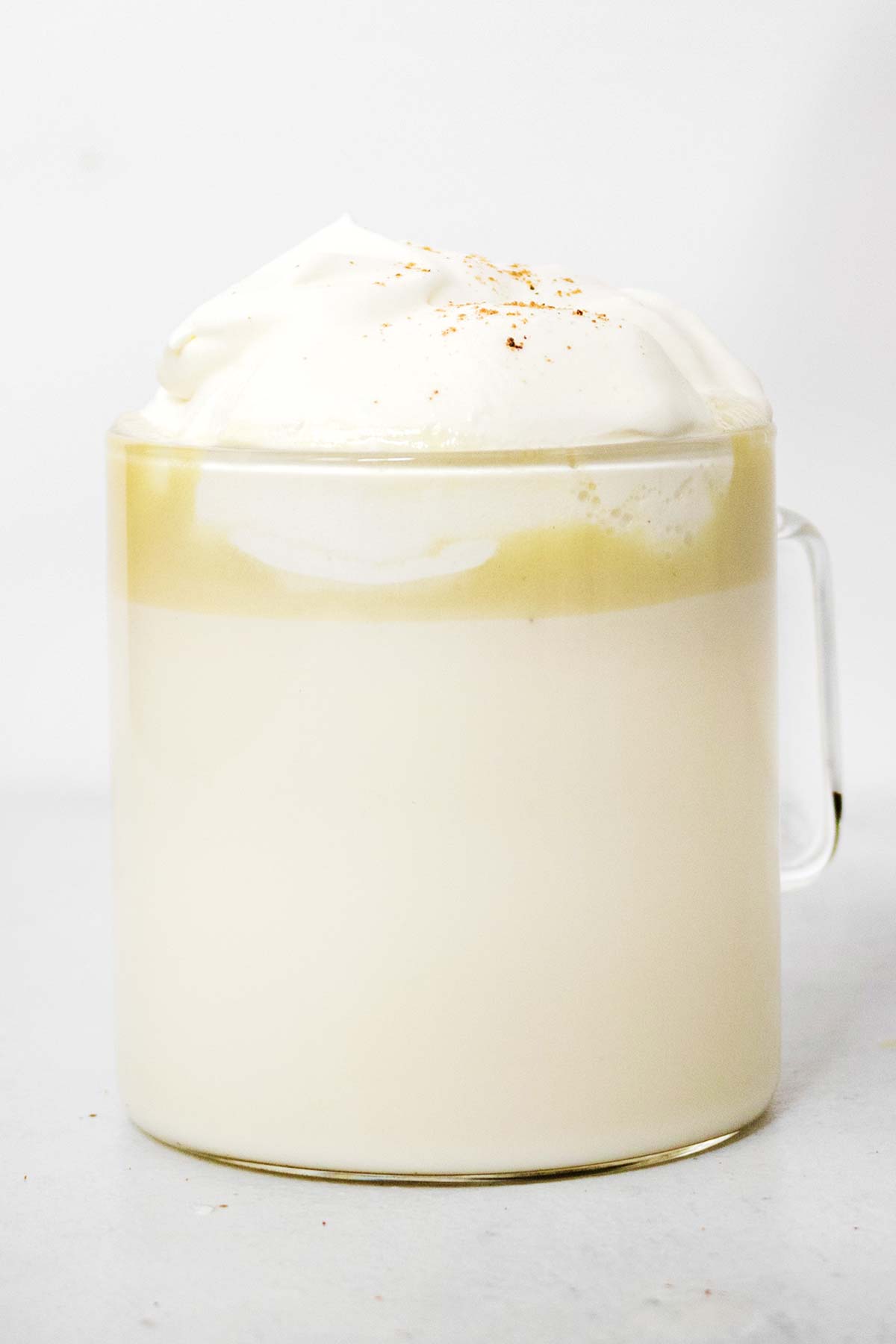 White hot chocolate with whipped cream in a glass mug.